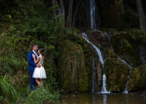 Romantic couple standing and looking at each other near the small waterfall.